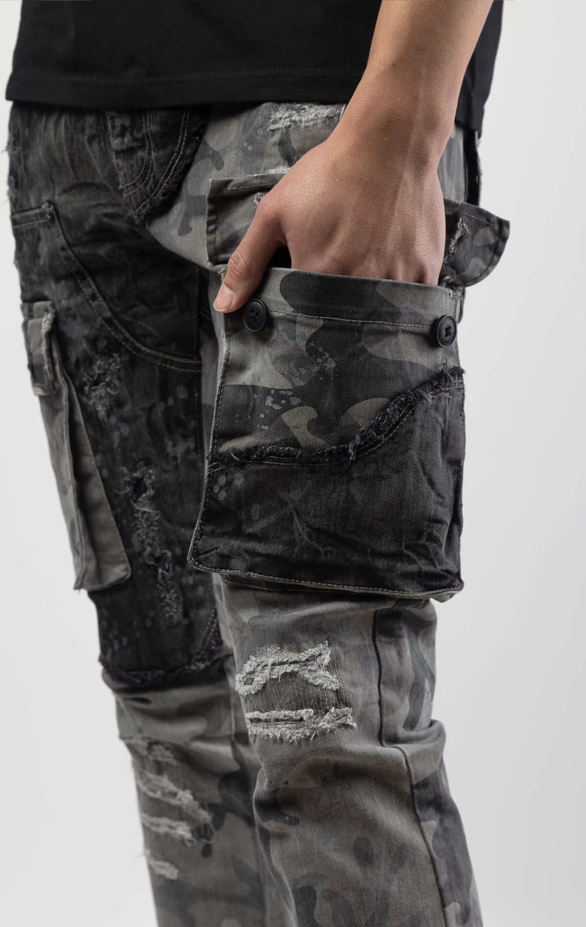 Black camo Extended length flare pant with a regular rise for maximum stacks. Skinny fit with hand-smearing and speckled paint splatter throughout. Rip and repair detailing, accompanied by cut & sewn woodland camouflage twill patches. Stitching repairs and deep front pocket bags, perfect for large smart phones.
